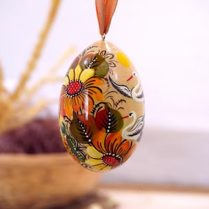 Handmålat påskägg i trä med motiv av stork och solros. Ukrainska påskägg med Petrykivka-målning. Pysanky folkkonst blommönster.