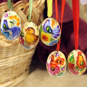 Puede incluir: Cinco huevos de Pascua de madera pintados a mano con diseños florales y de pájaros coloridos. Los huevos están colgados de cintas y son una decoración tradicional de Pascua.