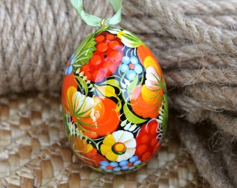 May include: A hand-painted Easter egg with a black background and colorful floral designs. The egg is decorated with red, orange, yellow, blue, and green flowers.
