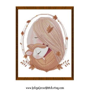 May include: Cross stitch pattern featuring a girl with long blonde hair hugging a fawn. The girl and fawn are surrounded by a wreath of leaves and flowers. The pattern is in shades of brown, pink, and white.