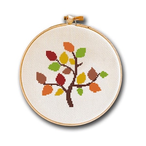 May include: A cross-stitch embroidery hoop with a brown tree with colorful leaves in shades of red, orange, yellow, and green.