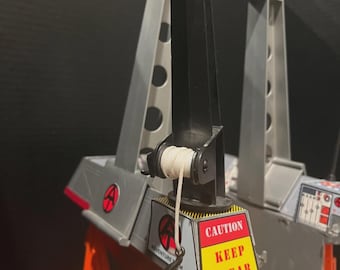 May include: A gray and orange toy crane with a black arm and a white rope. The crane has a red and black logo and a yellow and red sign that says "CAUTION KEEP CLEAR". The toy is a part of the Adventure Team.