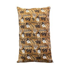 May include: A brown pillow with a repeating pattern of the Wake Forest University Demon Deacons logo. The logo features a black and white mascot wearing a top hat and the letters "WF" in gold.