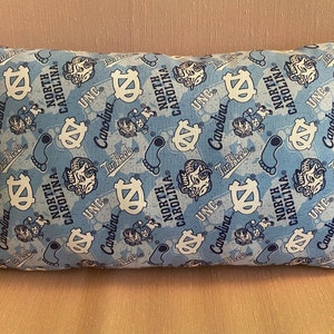 May include: A blue and white pillow with a repeating pattern of the University of North Carolina Tar Heels logo, mascot, and the words "UNC" and "North Carolina".
