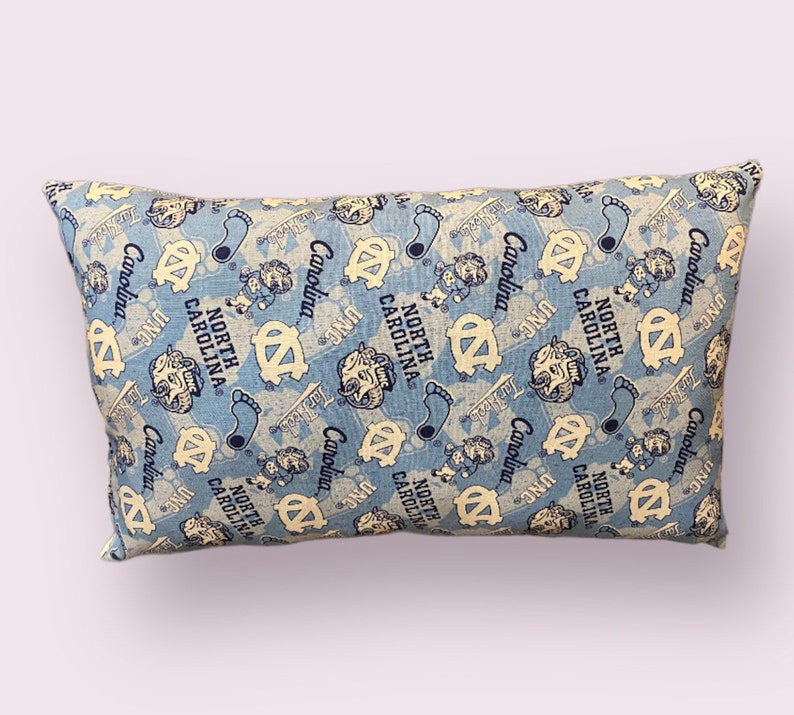 May include: A blue and white pillow with a repeating pattern of the University of North Carolina Tar Heels logo and the words "Carolina" and "North Carolina".