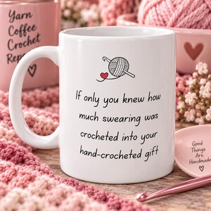 May include: A white ceramic mug featuring a black line drawing of a ball of yarn with a crochet hook and a small red heart. The text reads: If only you knew how much swearing was crocheted into your hand-crocheted gift. The mug has a handle.