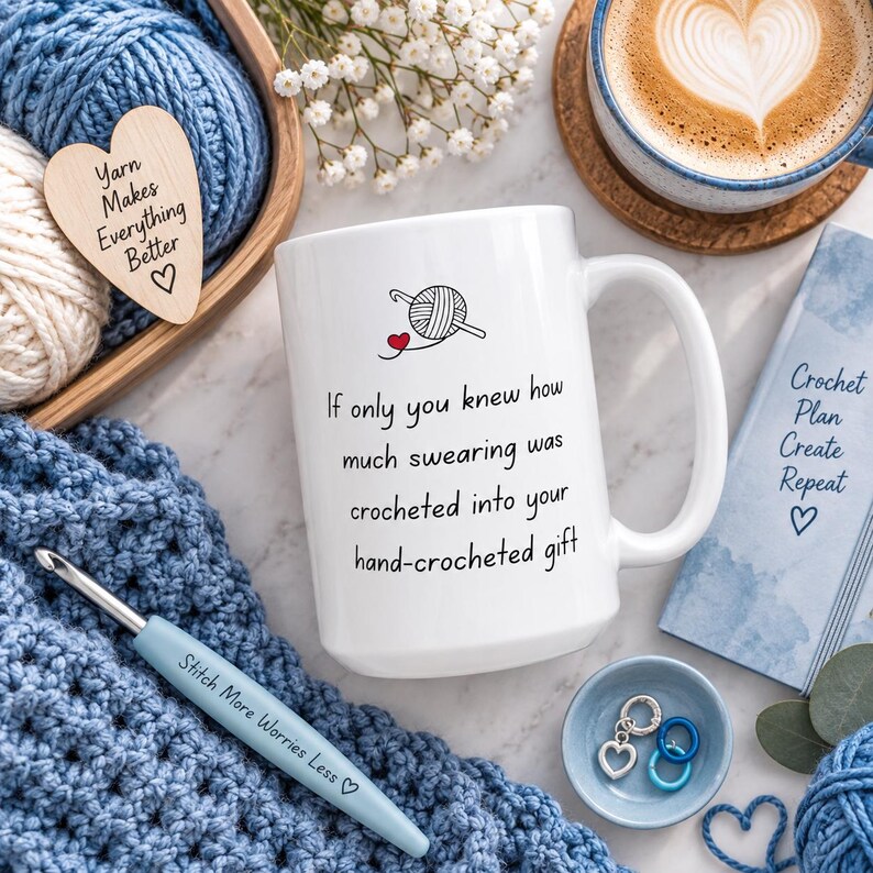 May include: A white ceramic mug featuring a black graphic of a yarn ball and crochet hook with a red heart, and the text: If only you knew how much swearing was crocheted into your hand-crocheted gift. The mug is surrounded by blue yarn.