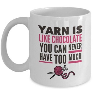 May include: White ceramic mug with a black and pink design. The mug reads "Yarn is like chocolate you can never have too much". A pink ball of yarn with two knitting needles is pictured below the text.