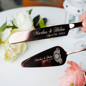 May include: Rose gold cake cutting set with a serrated knife and a spreader. The knife and spreader are engraved with the text "Markus & Helen April 25, 2024".