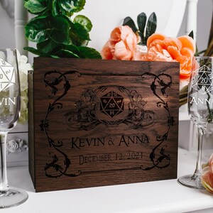 May include: A wooden box with a 20-sided die design and the text "Kevin & Anna December 12, 2021". Two champagne flutes with 20-sided die designs are on either side of the box. The flutes are engraved with the names "Kevin" and "Anna".