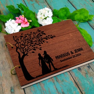 May include: A wooden photo album with a silhouette of a couple walking under a tree. The album is engraved with the text "MARKUS & JENNI September 20, 2016".
