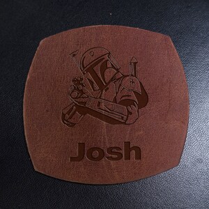 Puede incluir: Posavasos de cuero marr&oacute;n con una imagen grabada con l&aacute;ser de un personaje de Star Wars, Boba Fett, y el nombre "Josh".