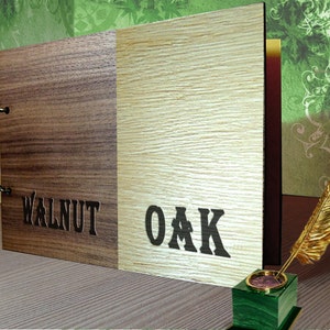 May include: A wooden photo album with a walnut and oak cover. The album is closed and has two metal hinges. The words "WALNUT" and "OAK" are printed on the cover.