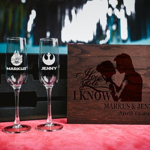 May include: Two champagne flutes with Star Wars themed engravings, one with the Millennium Falcon and the other with the Rebel Alliance symbol. The flutes are in a black box with a wooden lid that says "I love you, I know" with a silhouette of Han Solo and Princess Leia. The lid also has the names "Markus & Jenni" and the date "April 15, 2019".