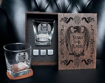 May include: Two clear glass tumblers, three metallic whiskey stones, and a dark wooden box. The glasses and the box lid are engraved with a dragon crest and the text "Tears of My Players" along with a twenty-sided die graphic.