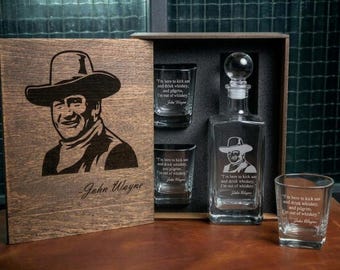 May include: A wooden gift box featuring a laser-engraved portrait of John Wayne and his signature. Inside are two glass tumblers and a glass decanter, each etched with the quote, I'm here to kick ass and drink whiskey, and pilgrim, I'm out of whiskey.