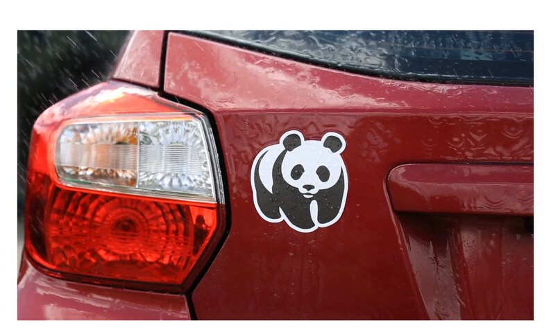 May include: A red car with a black and white panda sticker on the back.
