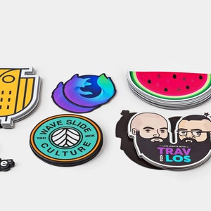 May include: Assortment of colorful stickers featuring various designs, including an owl, a watermelon, a car, a building, and a logo for OpenTable. The stickers are printed on white paper and have a glossy finish.