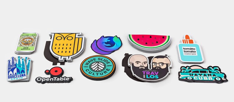 May include: Assortment of colorful stickers featuring various designs, including an owl, a watermelon, a car, a building, and a logo for OpenTable. The stickers are printed on white paper and have a glossy finish.
