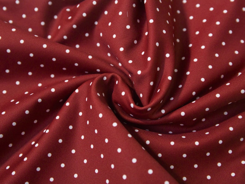 May include: Red fabric with white polka dots. The fabric is folded and textured.