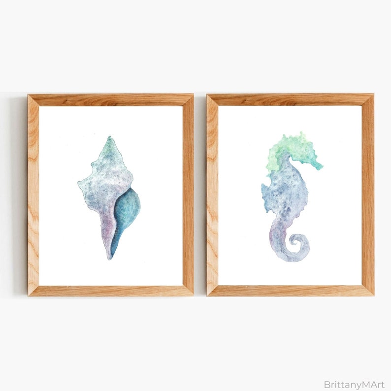 May include: Two framed watercolor paintings of sea life. The left painting features a blue and purple seashell. The right painting features a blue and green seahorse.