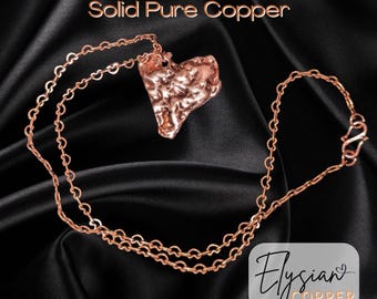 Puede incluir: Un collar con un colgante de corazón de cobre y una cadena. El colgante es texturizado y tiene un aspecto rústico. La cadena es una cadena simple de eslabones. El texto "Solid Pure Copper" está en la parte superior de la imagen. El texto "Elysian COPPER" está en la parte inferior de la imagen.