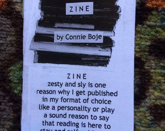 May include: A white booklet with black text titled "ZINE" by Connie Boje. The text reads "ZINE zesty and sly is one reason why I get published in my format of choice like a personality or play a sound reason to say that reading is here to stay and self-publishing MAY."