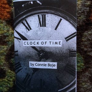 Pode incluir: Uma fotografia a preto e branco de um mostrador de relógio com algarismos romanos. O texto "CLOCK OF TIME" e "by Connie Boje" está impresso na imagem.