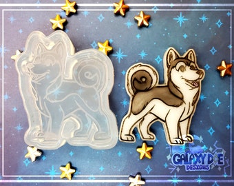 May include: A clear silicone mold of a cartoon husky dog with a curled tail. The mold is on a blue background with gold stars. The mold is for making resin crafts.