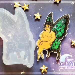 May include: A silicone mold of a fairy with green wings, sitting with her legs crossed. The mold is next to a finished resin casting of the fairy, with glitter embedded in the wings.