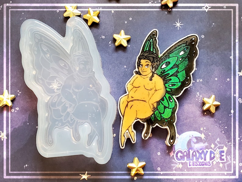 May include: A silicone mold of a fairy with green wings, sitting with her legs crossed. The mold is next to a finished resin casting of the fairy, with glitter embedded in the wings.