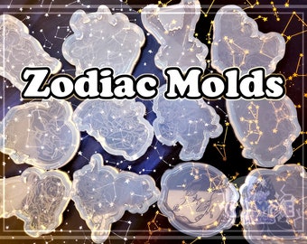May include: A set of 12 clear silicone molds featuring the zodiac signs. Each mold is shaped like a constellation with a star pattern. The molds are on a blue background with gold stars.