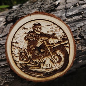 Może przedstawiać: Drewniany okrąg z wypalonym obrazem szkieletu jadącego na motocyklu. Okrąg zawiera tekst "Pierre 11-18-2012" oraz trójkąt 12 kroków z napisami "Jedność, Służba, Odzyskanie" i liczbą "XII".