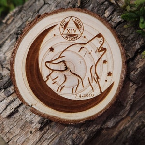 May include: A wooden circle with a wolf howling at the moon, surrounded by stars. The circle also features a triangle with the words "Unity, Service, Recovery" and the number "XIV" inside. The date "7.4.2010" is inscribed below the wolf.