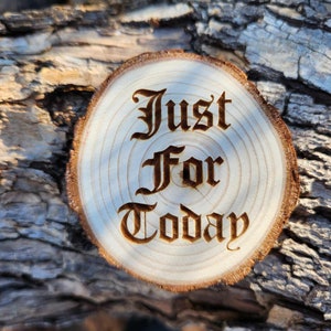 May include: A wooden round slice with the words "Just For Today" burned into the surface in a gothic font.