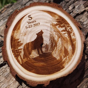 May include: A wooden slice with a wolf howling at the moon, surrounded by trees. The text "5 Years 5-22-2019" is engraved on the wood.