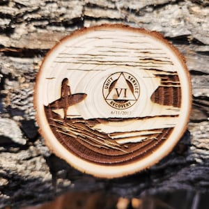 May include: A wooden circle with a surfer silhouette and a triangle with the words "Unity, Service, Recovery" and the number "VI" inside. The date "6/11/2017" is below the triangle.
