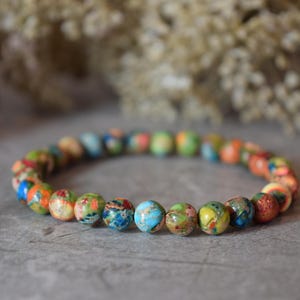 Peut inclure: Un bracelet en perles colorées composé de petites pierres rondes multicolores. Le bracelet est composé de différentes couleurs, notamment le bleu, le vert, le jaune, l'orange et le rouge.