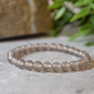 May include: A grey gemstone bracelet with round beads. The bracelet is made of natural stones and is designed to be worn on the wrist.