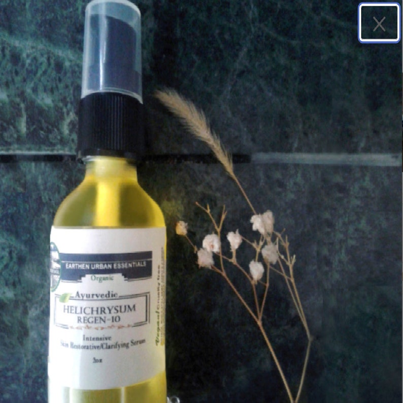 Puede incluir: Una botella de vidrio transparente con un l&iacute;quido amarillo en su interior. La botella tiene una tapa negra y una etiqueta blanca que dice "EARTHEN URBAN ESSENTIALS Organic Ayurvedic HELICHRYSUM REGEN-10 Intensive Skin Restorative Clarifying Serum 30ml".
