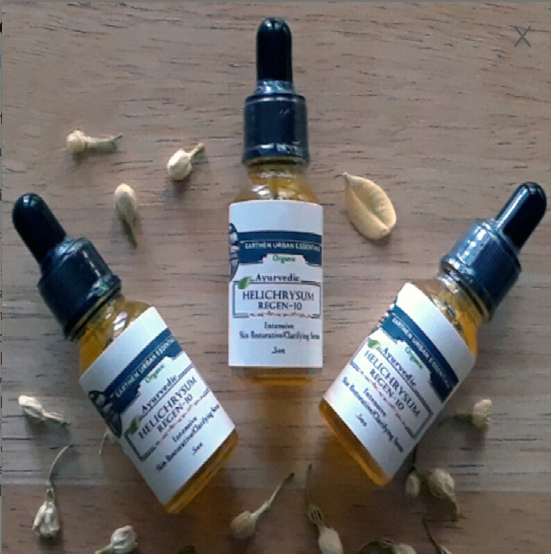 Puede incluir: Tres botellas de vidrio &aacute;mbar con goteros azules y etiquetas blancas. Las etiquetas tienen el texto "Ayurvedic, Helichrysum Regen-10, Suero Clarificante y Rejuvenecedor Intensivo para la Piel".