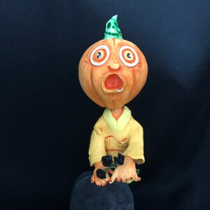 Großer Wackelkopf-Kürbis vor Grab Bonbon-Behälter