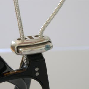 The Mechanical Knot is a sterling silver eyewear saver. It locks your glasses on its 20 inch  snake chain safely while looking stylish