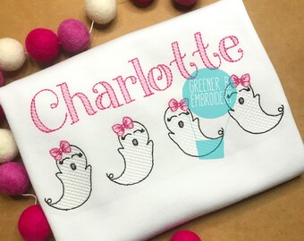 May include: White t-shirt with the name "Charlotte" embroidered in pink. Three embroidered ghosts with pink bows are on the shirt. The text "Greener Past Embroidery" is also embroidered on the shirt.