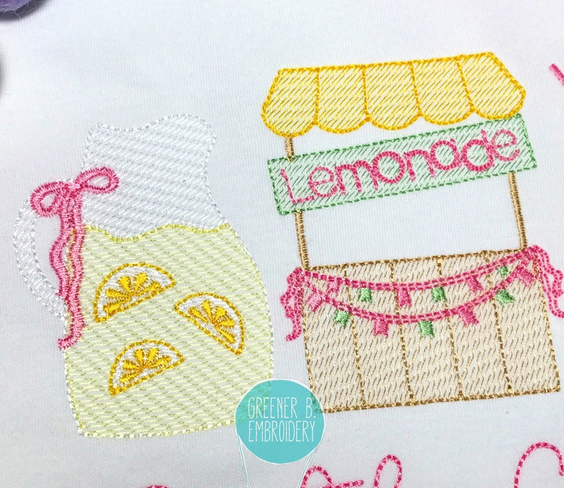 Puede incluir: Dise&ntilde;o bordado de un puesto de limonada con una jarra de limonada y limones. El puesto tiene un letrero que dice "Lemonade" y una guirnalda rosa y verde.