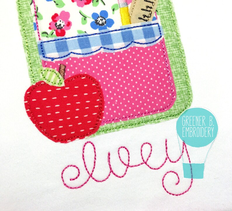 May include: A white fabric with a pink and green applique of a school bag with a red apple and the word "elvey" embroidered in pink thread. The text "Greener B. Embroidery" is in a blue balloon shape.