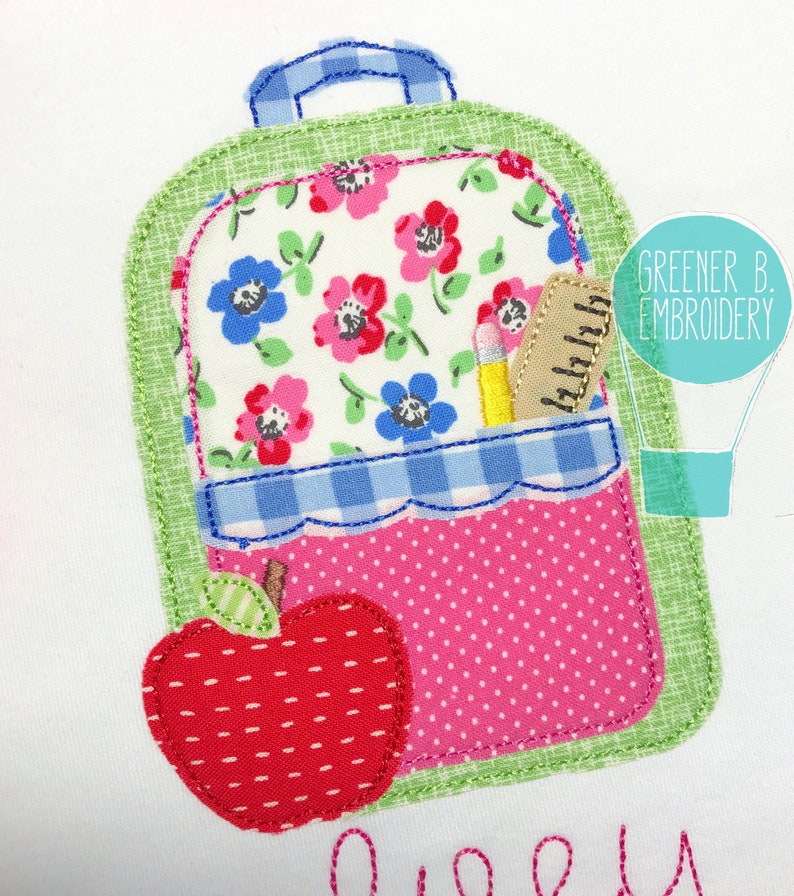 May include: A green and pink fabric applique of a backpack with a red apple and a pencil and ruler in the pocket. The backpack has a floral pattern and a blue and white checkered pocket.