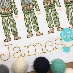Puede incluir: Dise&ntilde;o bordado de cinco soldados con uniformes verdes y marrones con el nombre Jameson en letras doradas debajo. El dise&ntilde;o est&aacute; sobre un fondo de tela blanca.