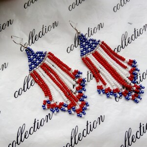 Peut inclure: Une paire de boucles d'oreilles en perles avec un motif rouge, blanc et bleu ressemblant au drapeau am&eacute;ricain. Les boucles d'oreilles sont faites de petites perles et ont une apparence de frange.
