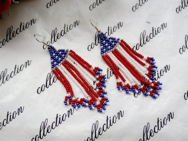 Peut inclure: Une paire de boucles d'oreilles en perles avec un motif rouge, blanc et bleu ressemblant au drapeau am&eacute;ricain. Les boucles d'oreilles sont faites de petites perles et ont une apparence de frange.